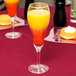 A Libbey tulip champagne glass filled with orange and yellow juice on a table in a brunch café.