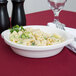 A Tuxton white round au gratin dish filled with pasta, broccoli, and cheese on a table.