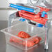 A Prince Castle tomato slicer on a counter with a container of tomato slices.