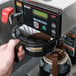 A person using a Bunn Axiom 15-3 coffee maker to make coffee.
