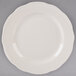A Tuxton ivory china plate with a scalloped edge on a gray background.