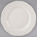 A Tuxton ivory china plate with a scalloped edge and a white rim.