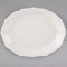 A white Tuxton oval china platter with a scalloped edge.