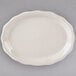 A white oval Tuxton china platter with a scalloped edge.