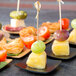 Tablecraft black bamboo square dishes holding a variety of fruit and vegetable appetizers.