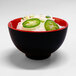 A Karma black and red melamine bowl with noodles and jalapenos.