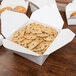 A table with a white Fold-Pak Bio-Pak take-out box full of cookies.