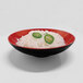 A Karma black and red melamine bowl filled with noodles and jalapenos.