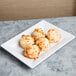 A white Elite Global Solutions rectangular melamine plate with coconut cookies on it.