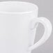 A close-up of a white mug with a white handle.