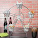 A Clipper Mill chrome ferris wheel rack with 5 baskets of food and drinks on a table.