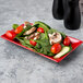 A red and black rectangular melamine plate with a salad.