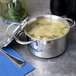 A Clipper Mill stainless steel mini bistro serving pot filled with soup and a lid on a table.