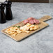 An Elite Global Solutions rectangular faux driftwood serving board with cheese and meat on it.