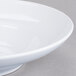 A close-up of a white Elite Global Solutions melamine bowl with a rim.