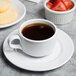 A white Elite Global Solutions double well melamine coffee saucer with a cup of coffee and a bowl of strawberries on it.