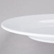 A close-up of a white Elite Global Solutions round melamine plate with a rim.