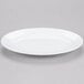 A white Elite Global Solutions oval melamine plate with a rim.