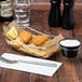 A Clipper Mill stainless steel boat basket with condiment holder on a table with food in it.