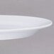 A close-up of a white Elite Global Solutions oval melamine plate with a rim.