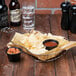 A Clipper Mill guitar basket with condiment holder filled with chips on a table with salsa and a bottle of beer.