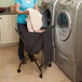 A woman using a Black Mobile Spring Loaded Laundry Lifter Hamper to put towels in a washing machine.