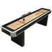 An Atomic platinum shuffleboard table with four balls and two wooden sticks.