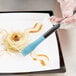 A person using a Mercer Culinary silicone brush to plate spaghetti.