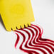 A yellow plastic spatula with red liquid flowing out.
