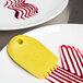 A yellow spatula with red and white stripes (Mercer Culinary 3mm Graduated Lancet Arch Silicone Wedge Plating Tool)
