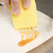 A person using a Mercer Culinary saw tooth edge silicone wedge to spread caramel on a white plate.