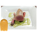 A white plate with a piece of meat and a Mercer Culinary yellow silicone plating tool in the shape of a horseshoe.