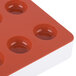 A red silicone round tray with 24 fruit jelly compartments.