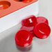 A red silicone round mold with small fruit jelly candies.