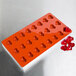 A red silicone heart-shaped mold with 24 compartments.