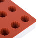 A red and white Martellato silicone mold with 24 fruit jelly compartments.