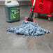 A Rubbermaid Blue Blend Looped End Wet Mop in a red bucket next to a bucket of detergent.