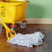 A blue and white Rubbermaid wet mop head with a yellow bucket and mop on the floor.