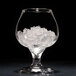 A glass with ice inside sitting on a white surface.