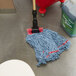 A Rubbermaid blue looped end wet mop head on the floor next to a mop bucket.