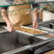 A person holding a Choice stainless steel steam table pan full of food.