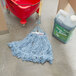 A Rubbermaid blue blend wet mop next to a red bucket and a container.