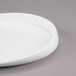 A close-up of a Libbey Royal Rideau white porcelain plate with a curved edge on a gray surface.