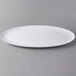 A white Libbey oval porcelain tray on a gray surface.