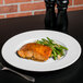A Libbey Royal Rideau white porcelain plate with salmon and green beans on a table with a fork.
