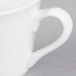 A close-up of a white Libbey tall tea cup with a handle.