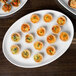 A Libbey white porcelain tray with mini quiches and other appetizers on a table.