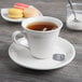 A Libbey white porcelain tea saucer with a cup of tea and cookies on it.