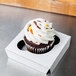 A Baker's Mark reversible cupcake insert holding a cupcake with white frosting and sprinkles in a white box.