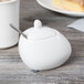 A white ceramic Libbey sugar pot with a spoon.